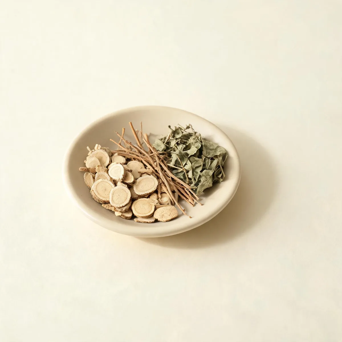 An editorial still life of the traditional Chinese herbs used for this condition, arranged on a warm off-white surface: pale root slices.