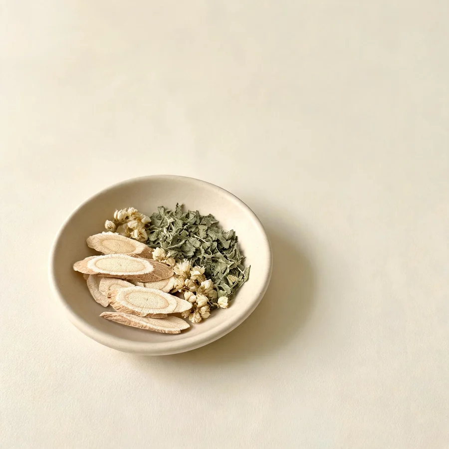 An editorial still life of the traditional Chinese herbs used for this condition, arranged on a warm off-white surface: pale cooling root.