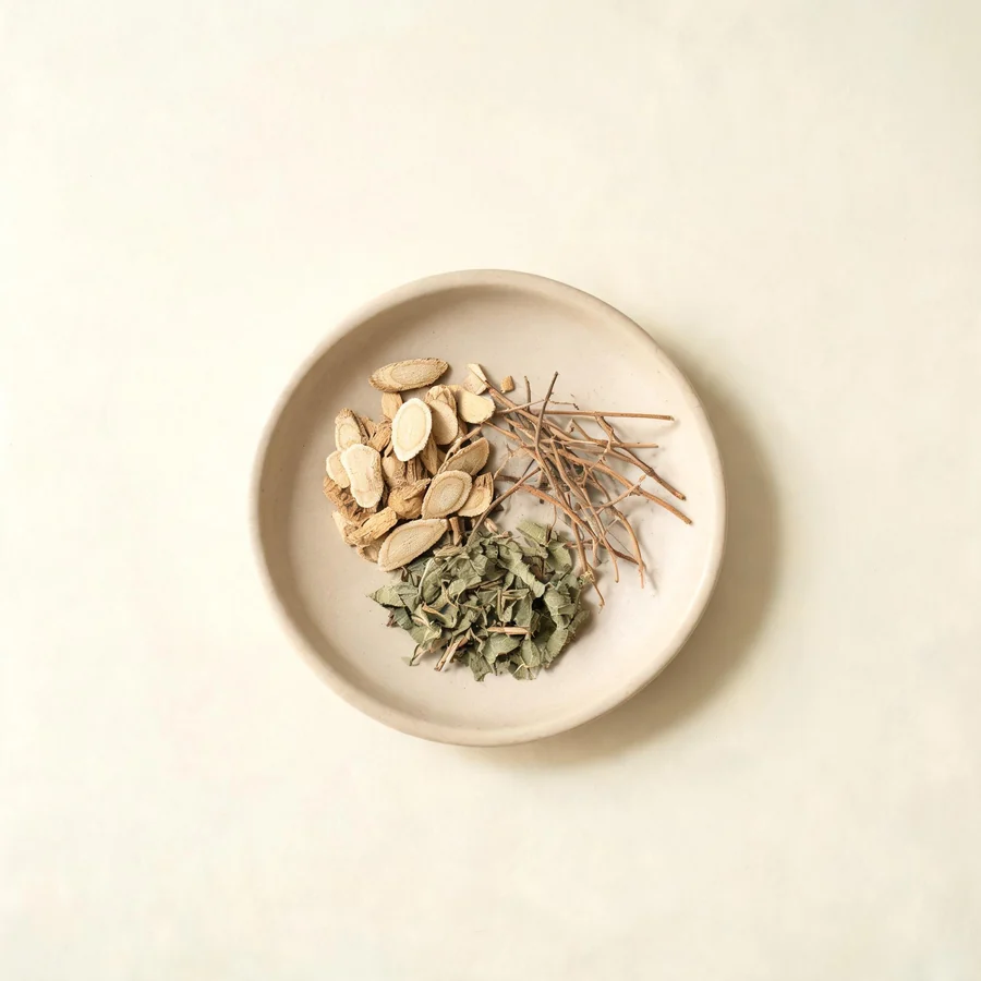 An editorial still life of the traditional Chinese herbs used for this condition, arranged on a warm off-white surface: pale root slices.