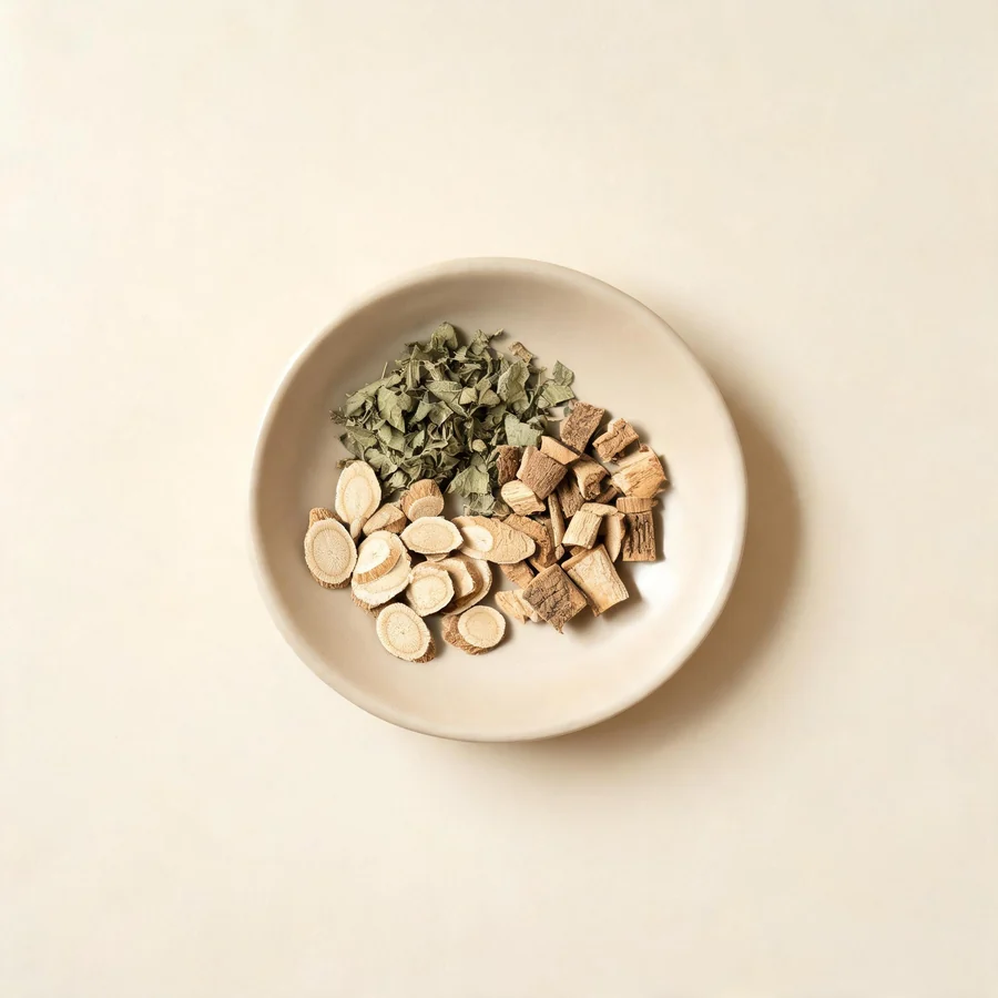 An editorial still life of the traditional Chinese herbs used for this condition, arranged on a warm off-white surface: pale root slices.