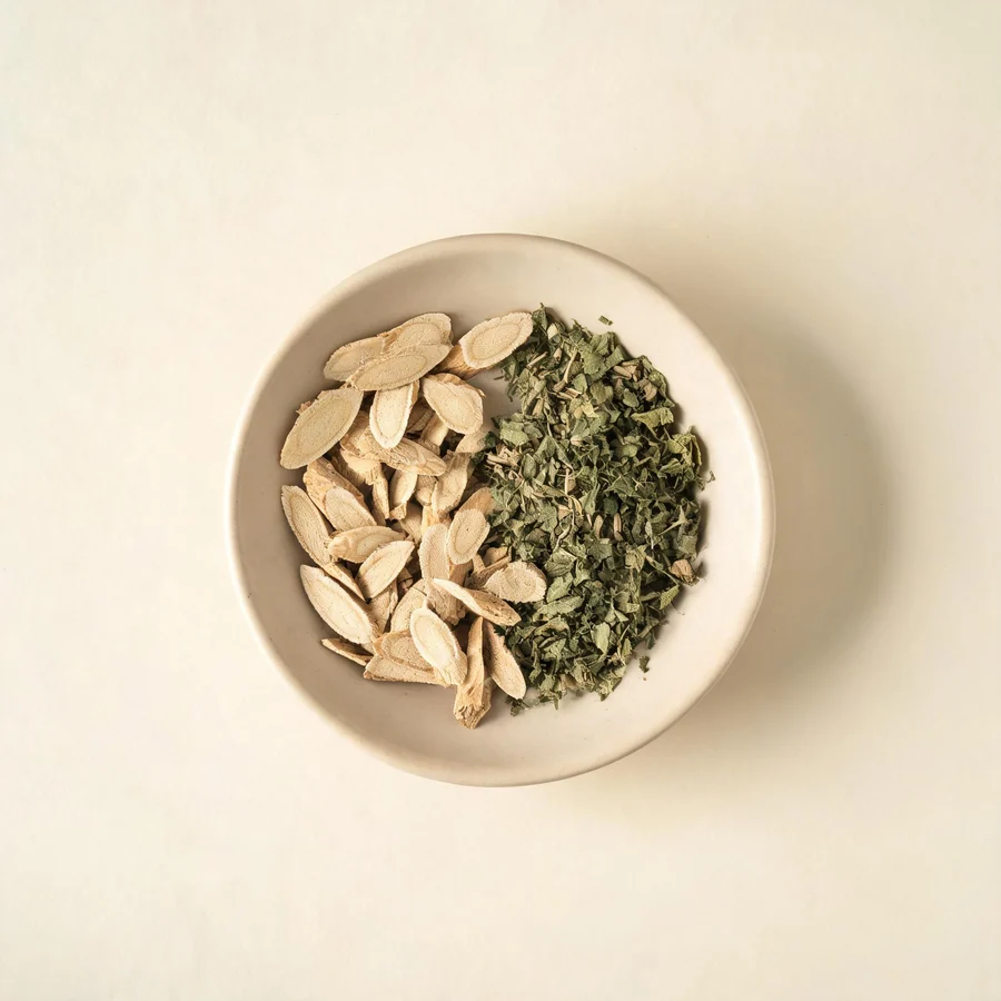 An editorial still life of the traditional Chinese herbs used for this condition, arranged on a warm off-white surface: pale cooling root.
