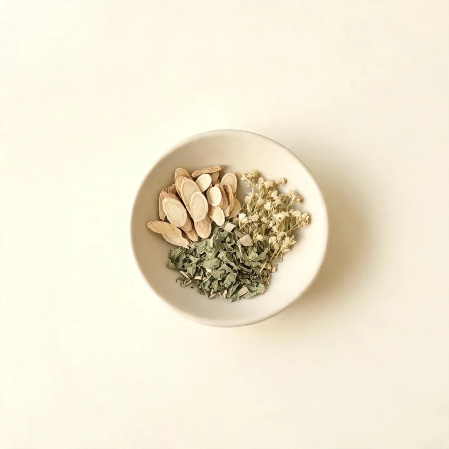 An editorial still life of the traditional Chinese herbs used for this condition, arranged on a warm off-white surface: pale cooling root.